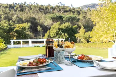 a table with two plates of food and wine glasses at Caledon Grace Guesthouse in Caledon