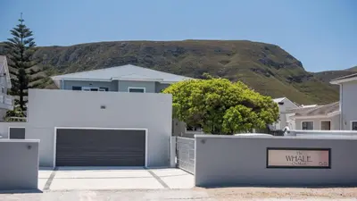 a white house with a garage with a sign that reads the white at The Whale on Main B&B in Hermanus
