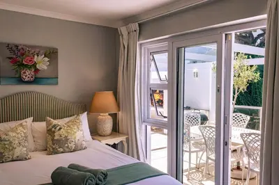 a bedroom with a bed and a balcony with a table at Hermanus Family Getaway - Near The Beach in Hermanus