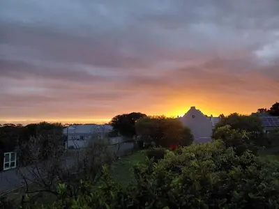 a sunset over a city with houses and trees at Nerf-af ROOMS at Onrus , Hermanus in Hermanus