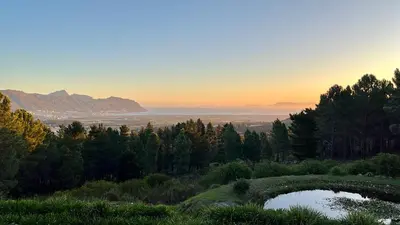 a view of the sunset from a hill with two ponds at Lalapanzi Lodge in Somerset West