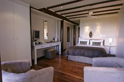 a bedroom with a bed and a tv and two chairs at Lalapanzi Lodge in Somerset West