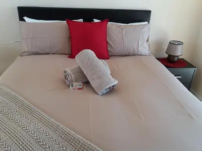 a bed with a towel and two pillows on it at Flamingo Palms in Table View