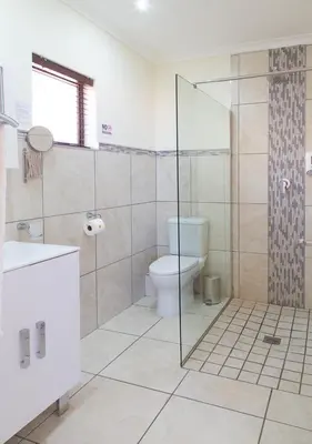 a bathroom with a toilet and a glass shower at Tyger Hills Guest House in Bellville