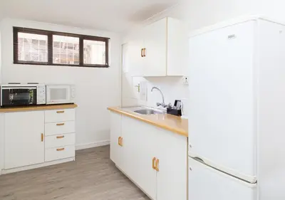 a kitchen with white cabinets and a sink at Tyger Hills Guest House in Bellville