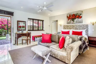 a living room with a couch and red pillows at Vredenburg Manor House in Somerset West