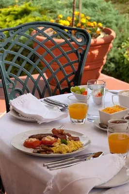 a table with a plate of breakfast food and orange juice at Vredenburg Manor House in Somerset West