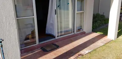 an open door of a house with a cat on the porch at 123 hbc in Hermanus