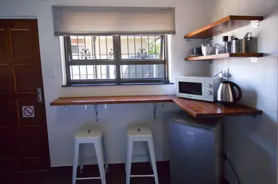 a kitchen with two bar stools and a microwave at Panorama Indlu in Cape Town