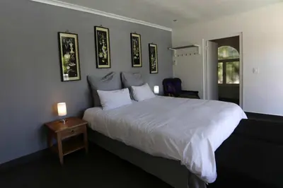 a bedroom with a white bed and a table with a lamp at Panorama Indlu in Cape Town