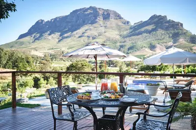 a table with food on it with a mountain in the background at Alluvia Boutique Winery & Luxury Accommodation in Stellenbosch