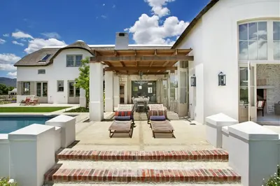 a house with a patio with chairs and a pool at Villa Simondium in Franschhoek