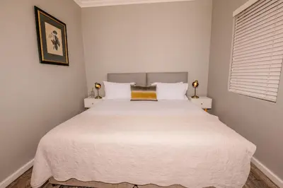 a bedroom with a large white bed with two night stands at The Corner House L'A-nnexe in Franschhoek