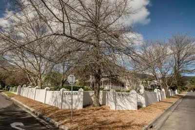 a tree in front of a white fence at The Corner House L'A-nnexe in Franschhoek