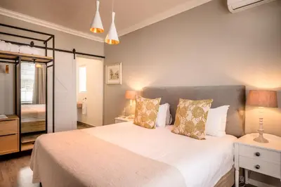 a bedroom with a large bed with white sheets and pillows at The Corner House L'A-nnexe in Franschhoek