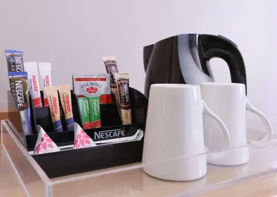 a tea pot and cups on a shelf with books at StayEasy Century City in Cape Town