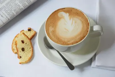 a cup of coffee and a cookie on a plate at StayEasy Century City in Cape Town