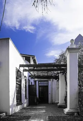 an entrance to a white building with a wooden gate at Mooiplaas Wine Estate in Stellenbosch