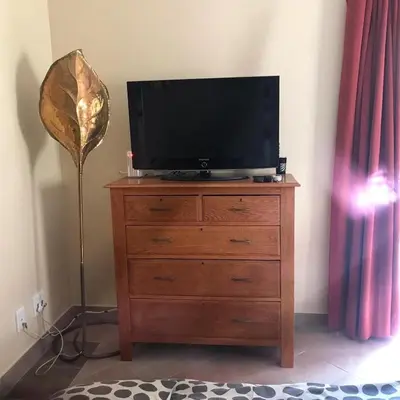 a television on top of a dresser with a lamp at Wine Cottage by the Sea in Helderberg