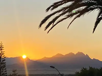 a sunset with mountains in the background and a street light at Four Palms Accommodation in Durbanville