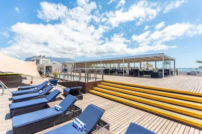 a deck with blue lounge chairs and a building at Lagoon Beach 237A by CTHA in Cape Town