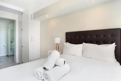 a bedroom with a large white bed with a black headboard at The Paragon 317 in Cape Town