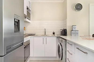a white kitchen with a sink and a dishwasher at The Paragon 317 in Cape Town