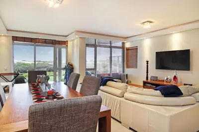 a living room with a couch and a table and a television at Dolphin Beach E5 in Bloubergstrand
