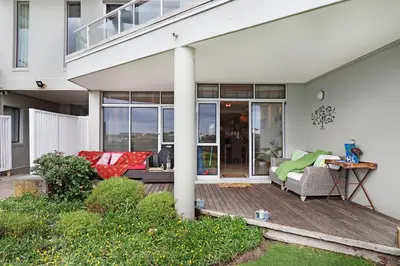 a porch of a house with a couch and chairs at Dolphin Beach E5 in Bloubergstrand