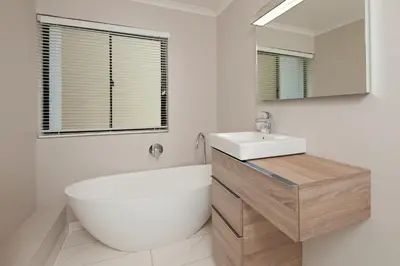 a bathroom with a tub and a sink and a mirror at The Sun, Whales & Waves - Seafront Apartment in Hermanus