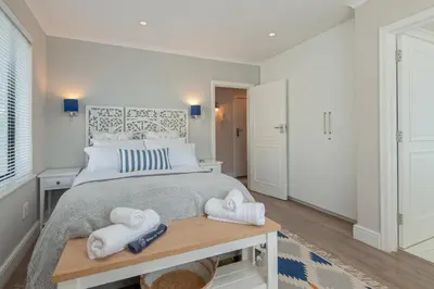 a bedroom with a large bed with towels on a table at The Sun, Whales & Waves - Seafront Apartment in Hermanus