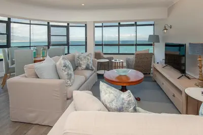 a living room with white furniture and a view of the ocean at The Sun, Whales & Waves - Seafront Apartment in Hermanus