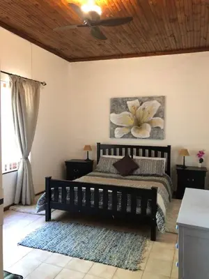 a bedroom with a bed with a flower painting on the wall at The Vineyard View in Joostenberg Vlakte