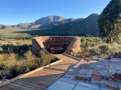 a stone bridge in a field with mountains in the background at Riverbend Farm in Robertson