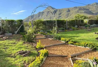 a garden with a fence and a garden with flowers at Ridgeworth Cottage in Greyton