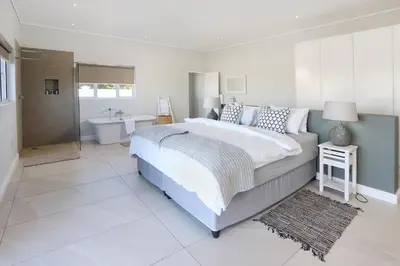a bedroom with a large bed and a bath tub at 269 on Main Holiday Home in Hermanus