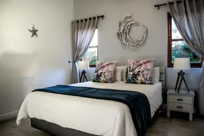 a bedroom with a bed and a mirror on the wall at Sixteen Guesthouse on Main in Hermanus