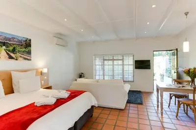 a bedroom with a large white bed and a desk at Albourne Guesthouse in Somerset West