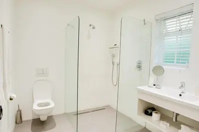 a white bathroom with a toilet and a glass shower at Albourne Guesthouse in Somerset West