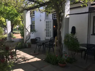 a patio with a table and chairs in front of a house at Albourne Guesthouse in Somerset West