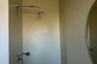 a shower in a bathroom with a white wall at Stay at Friends Economy Rooms in Malkopvlei