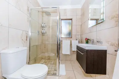 a bathroom with a shower and a toilet and a sink at Le Petit Chateau Guest House in Durbanville