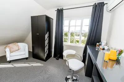 a room with a desk and a chair and a window at Le Petit Chateau Guest House in Durbanville