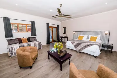 a living room with a bed and a couch at Le Petit Chateau Guest House in Durbanville