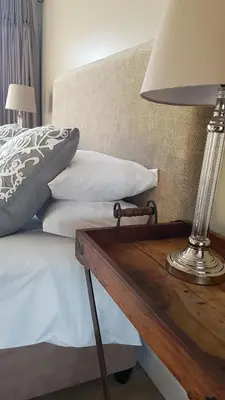 a lamp on a wooden table next to a bed at Franschhoek Village House in Franschhoek