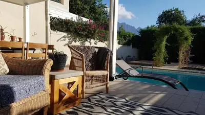 a patio with chairs next to a swimming pool at Franschhoek Village House in Franschhoek