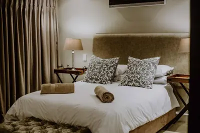 a bedroom with a large bed with white sheets and pillows at Franschhoek Village House in Franschhoek