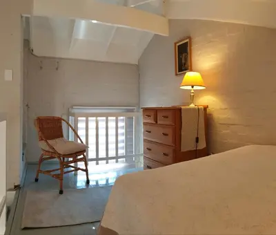 a bedroom with a bed and a chair and a lamp at Dawn's Place in Strand