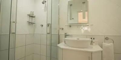 a white bathroom with a sink and a shower at Oakvale Lodge in Cape Town