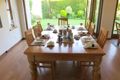 a wooden table in a dining room with chairs and a tableablish at Oakvale Lodge in Cape Town